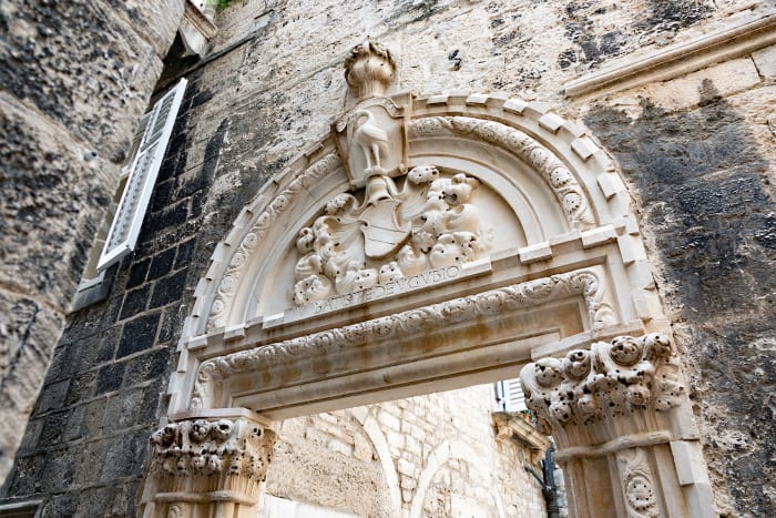 The entrance to the gothic Augubio Palace of the ennobled merchant Giovianni Battista De Gubbio from the 15th century. This ornate doorway lies inside the walls of Diocletian’s Palace, a well-preserved Roman structure in Split, dating back to the fourth century. 