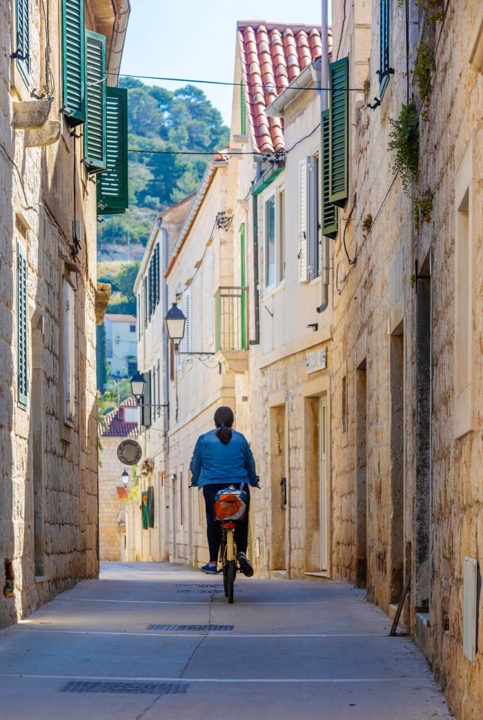 A cyclist pedals through the ancient narrow winding streets of Vis. Croatia has both continental and Mediterranean climates. Vineyards and olive groves are plentiful with lemons, mandarins, figs and almonds to the south. 