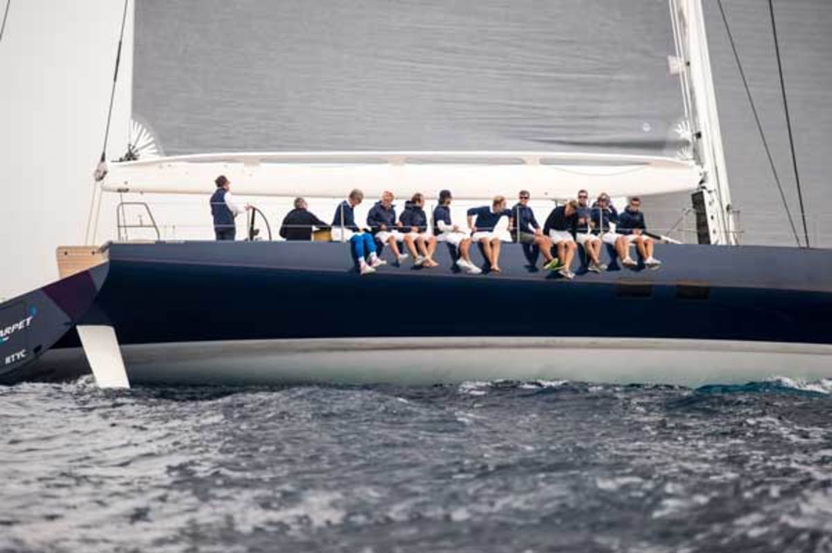With the wind beginning to fill the high-tech sails, the yacht's crew gets comfortable on the weather rail.