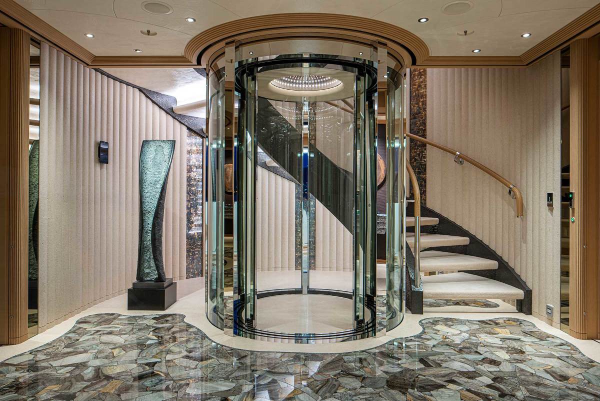 The main deck starboard-side entry to the guest accommodations with a central elevator and a sole inlaid with a mosaic of fossilized wood.