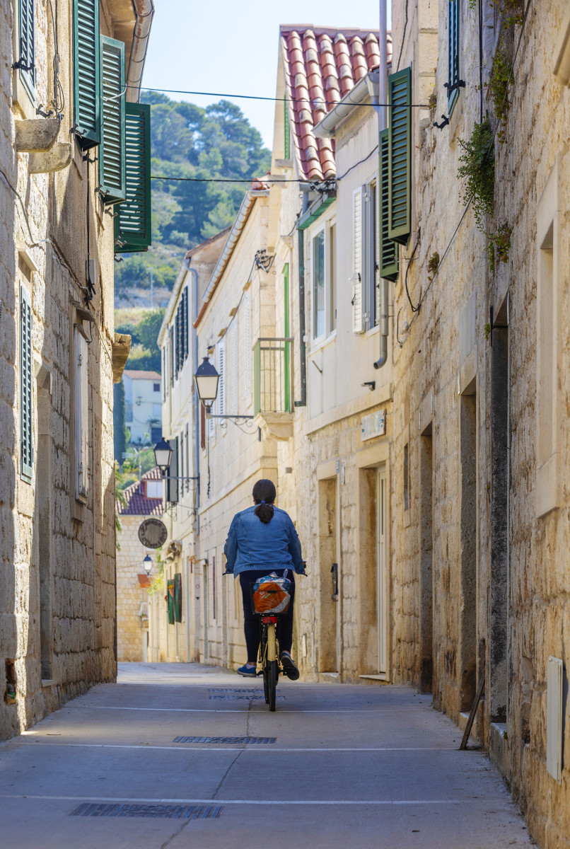 A cyclist pedals through the ancient narrow winding streets of Vis. Croatia has both continental and Mediterranean climates. Vineyards and olive groves are plentiful with lemons, mandarins, figs and almonds to the south. 